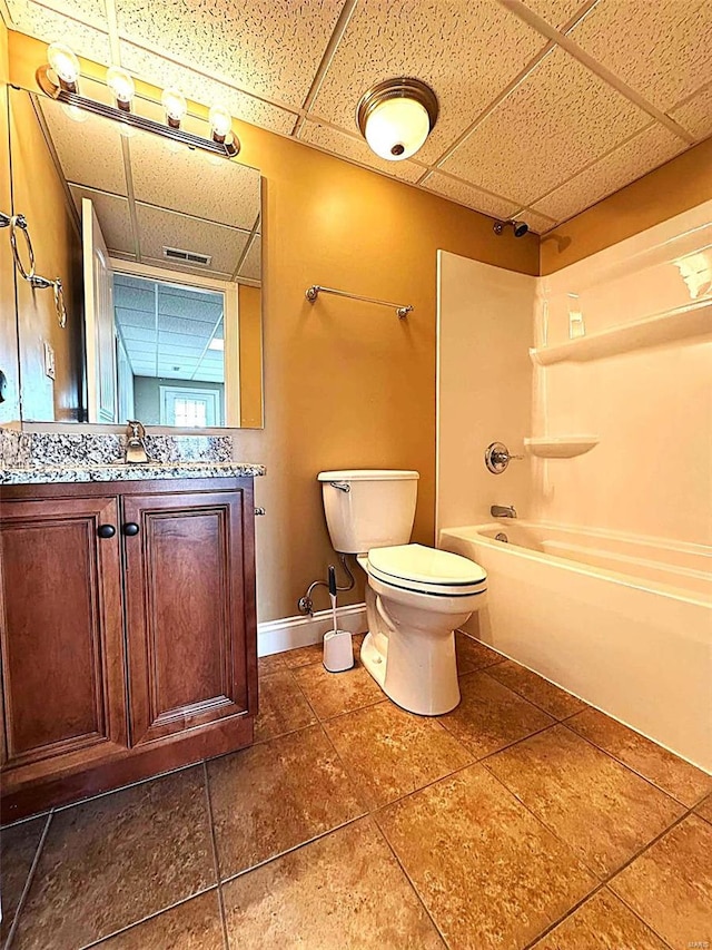 full bathroom featuring a drop ceiling,  shower combination, toilet, and vanity