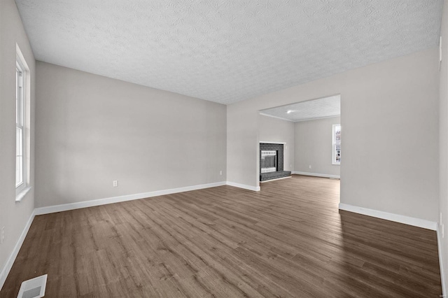 unfurnished living room featuring a textured ceiling, dark hardwood / wood-style floors, and a brick fireplace