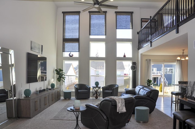 living room featuring carpet, a towering ceiling, and ceiling fan with notable chandelier