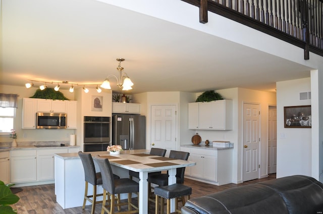 interior space with stainless steel appliances, decorative light fixtures, a chandelier, white cabinets, and dark hardwood / wood-style floors