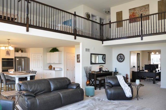 carpeted living room with a high ceiling and a notable chandelier