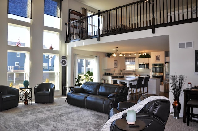 carpeted living room featuring a towering ceiling and an inviting chandelier