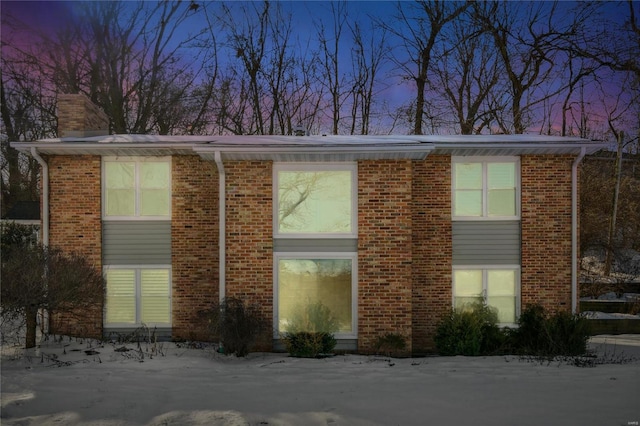 property exterior at dusk with brick siding and a chimney