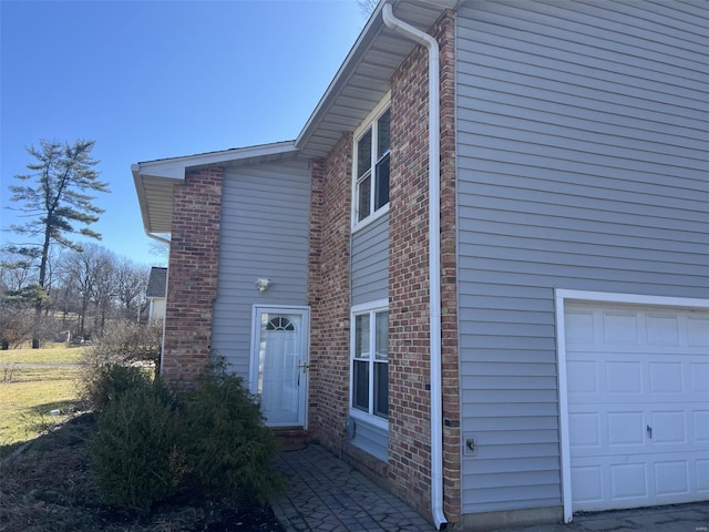 view of side of home featuring a garage and brick siding