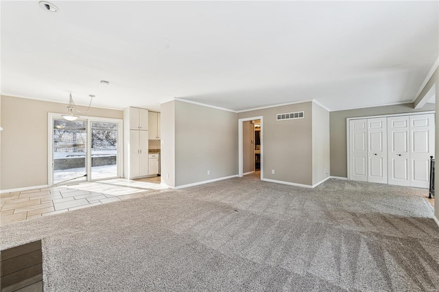 unfurnished living room featuring visible vents, baseboards, ornamental molding, and light colored carpet