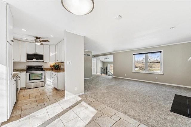 kitchen featuring stainless steel appliances, light colored carpet, open floor plan, white cabinets, and baseboards