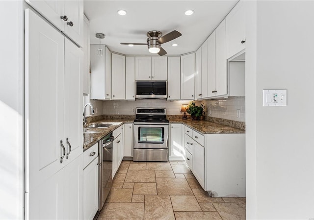 kitchen with stone tile floors, white cabinets, appliances with stainless steel finishes, dark stone countertops, and backsplash