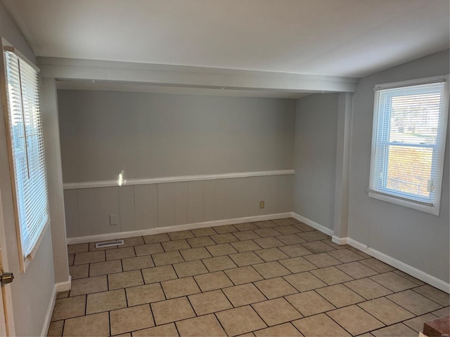 tiled spare room with plenty of natural light and lofted ceiling