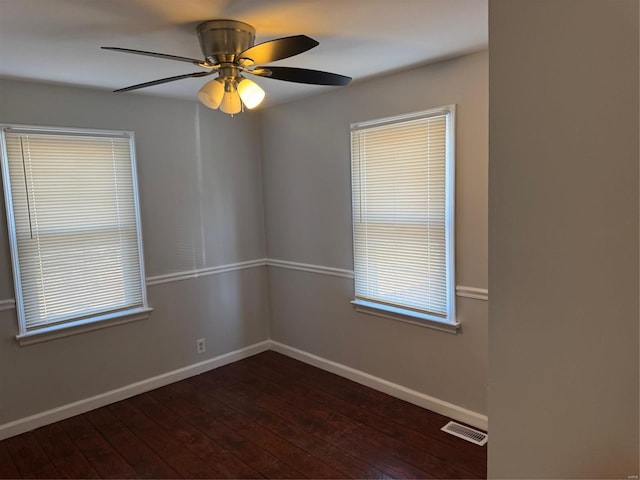 empty room with ceiling fan, a healthy amount of sunlight, and dark hardwood / wood-style flooring