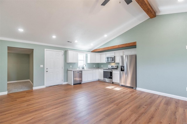 kitchen with light wood-type flooring, stainless steel appliances, sink, lofted ceiling with beams, and white cabinetry