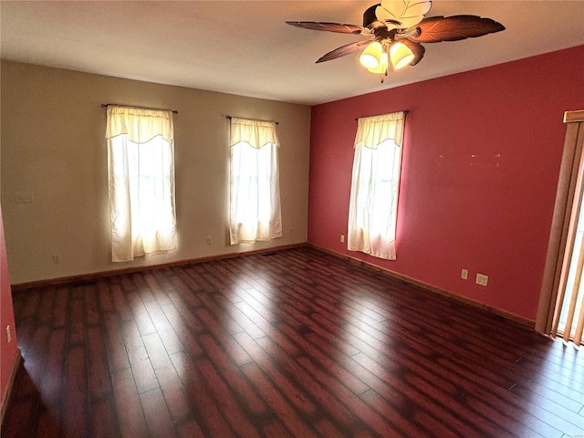 spare room with ceiling fan, a healthy amount of sunlight, and dark hardwood / wood-style flooring