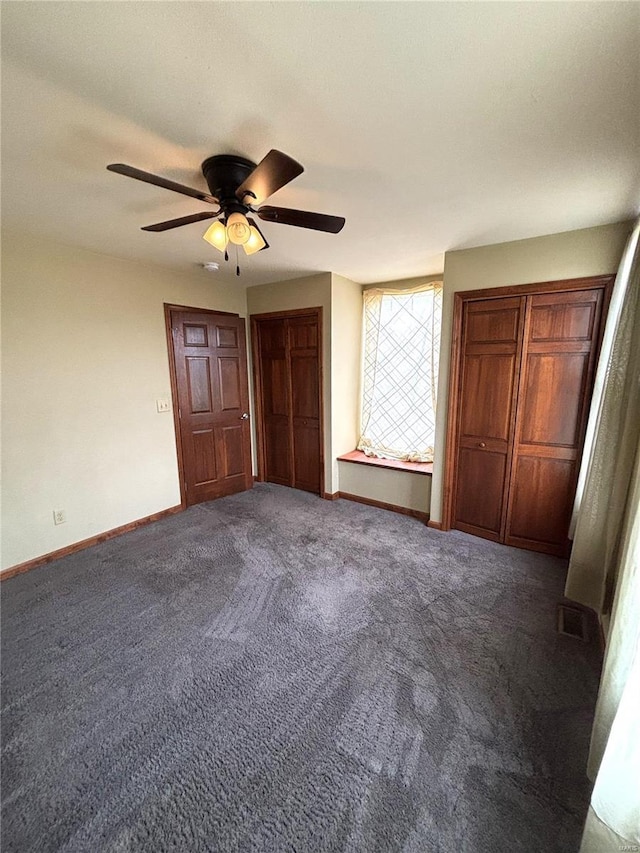 unfurnished bedroom with dark carpet and ceiling fan