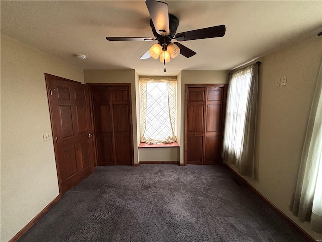 unfurnished bedroom featuring ceiling fan and dark carpet