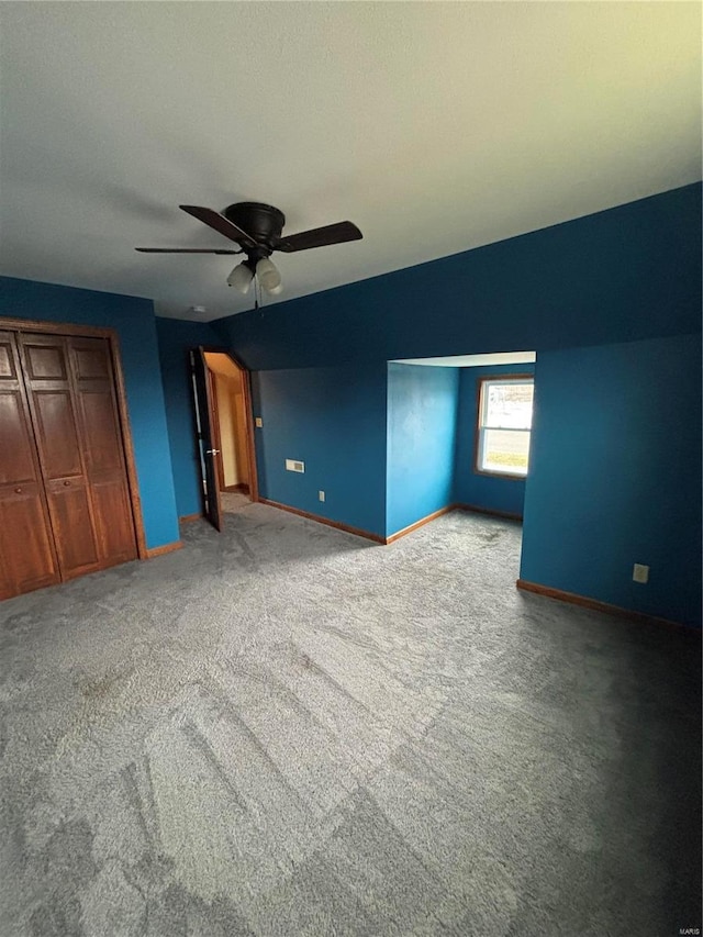 unfurnished bedroom with ceiling fan, a closet, and light colored carpet