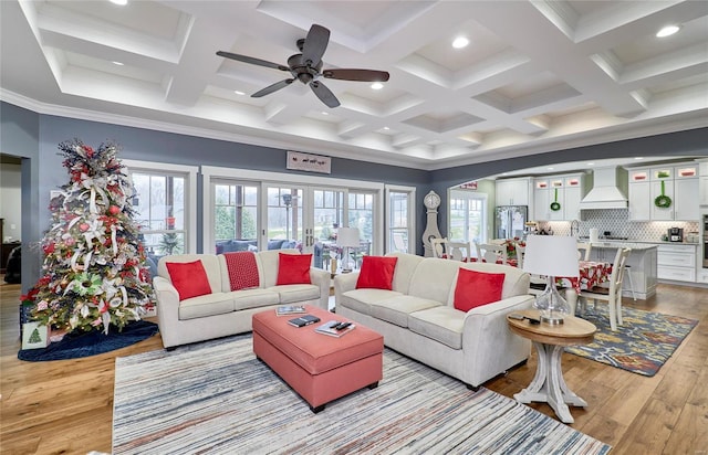 living room with beamed ceiling, ornamental molding, ceiling fan, light hardwood / wood-style flooring, and coffered ceiling