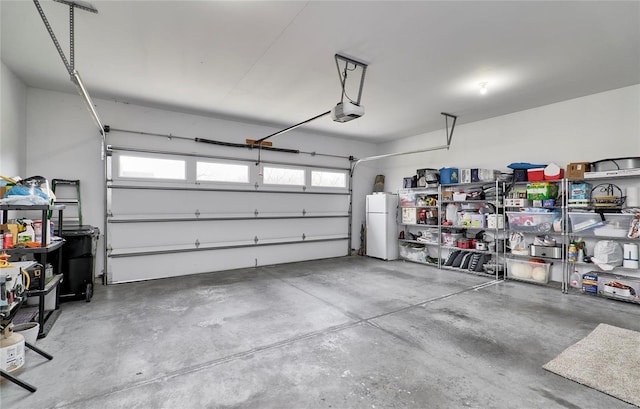 garage featuring white fridge and a garage door opener