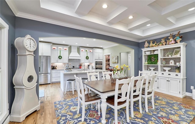 dining area with beamed ceiling, ornamental molding, coffered ceiling, and light hardwood / wood-style floors