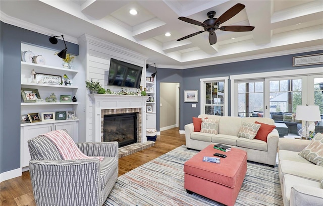 living room featuring beamed ceiling, a brick fireplace, coffered ceiling, and light wood-type flooring