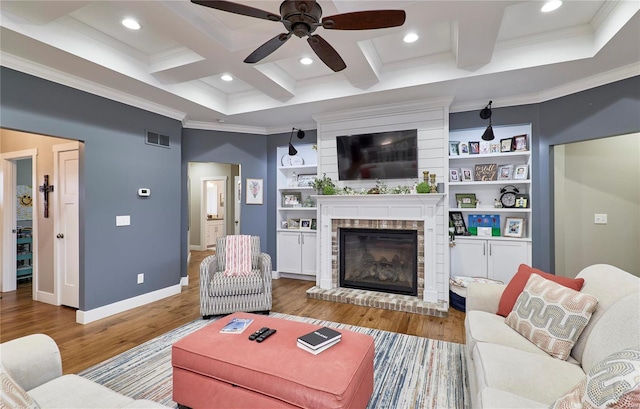 living room featuring coffered ceiling, beamed ceiling, crown molding, hardwood / wood-style flooring, and a fireplace