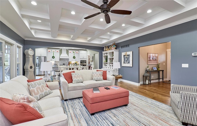 living room featuring beamed ceiling, coffered ceiling, ceiling fan, crown molding, and light wood-type flooring