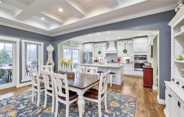 dining space featuring coffered ceiling, sink, light hardwood / wood-style flooring, ornamental molding, and beam ceiling