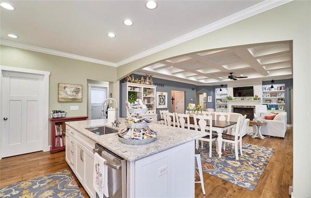 kitchen featuring sink, light stone counters, stainless steel dishwasher, a kitchen island with sink, and white cabinets