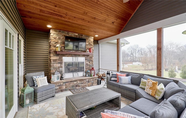 sunroom featuring wood ceiling, a healthy amount of sunlight, vaulted ceiling, and an outdoor stone fireplace