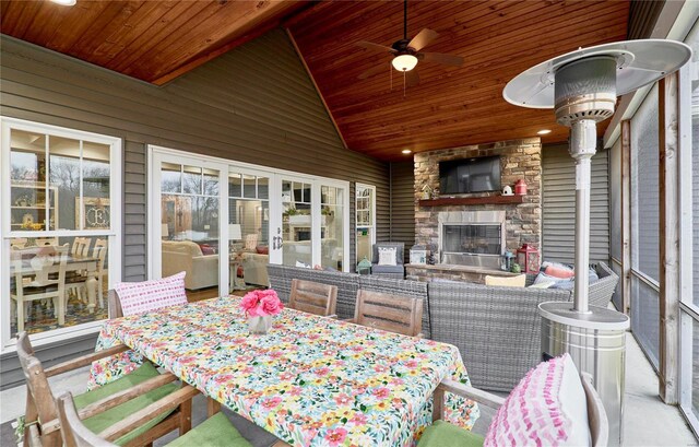 sunroom / solarium with an outdoor stone fireplace, lofted ceiling, ceiling fan, and wood ceiling