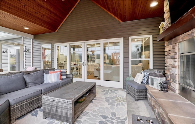 sunroom featuring french doors, an outdoor stone fireplace, vaulted ceiling, and wooden ceiling