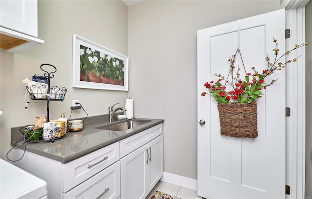 bar with washer / clothes dryer, white cabinetry, sink, and light tile patterned floors