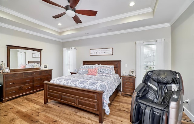 bedroom with ceiling fan, ornamental molding, a tray ceiling, and light hardwood / wood-style flooring