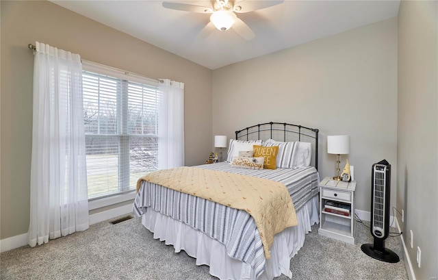 carpeted bedroom featuring heating unit, ceiling fan, and multiple windows