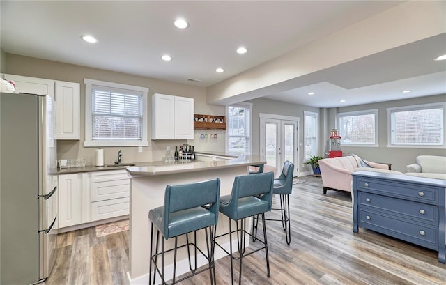 kitchen featuring a center island, white cabinets, stainless steel refrigerator, and a breakfast bar