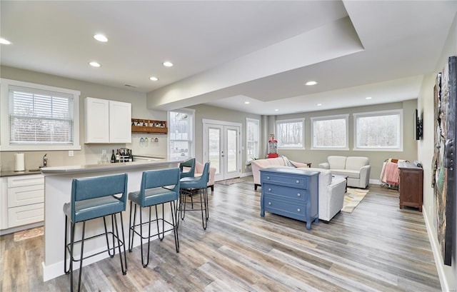 kitchen featuring blue cabinetry, white cabinetry, a kitchen bar, french doors, and light wood-type flooring