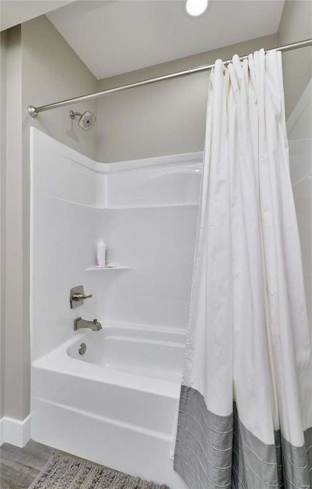 bathroom featuring wood-type flooring and shower / bathtub combination with curtain