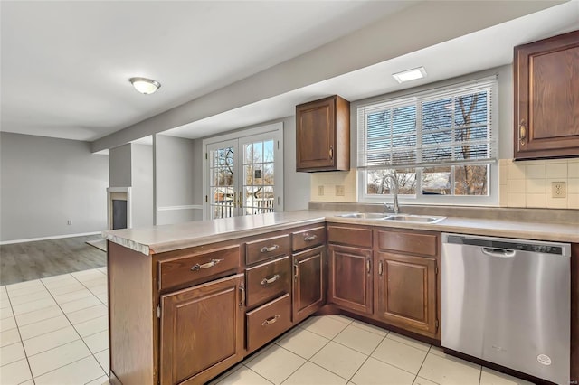 kitchen featuring dishwasher, sink, backsplash, kitchen peninsula, and light tile patterned flooring