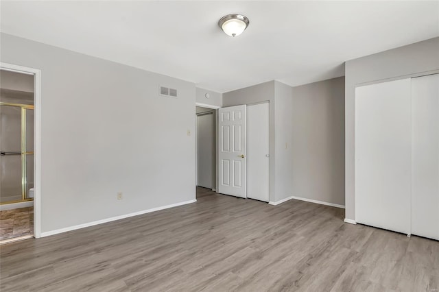 unfurnished bedroom featuring light wood-type flooring and ensuite bath