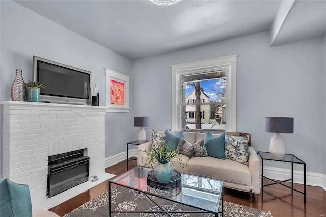 living room featuring dark hardwood / wood-style flooring and a brick fireplace