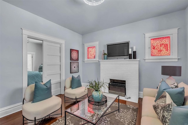 living area with baseboards, wood finished floors, and a fireplace