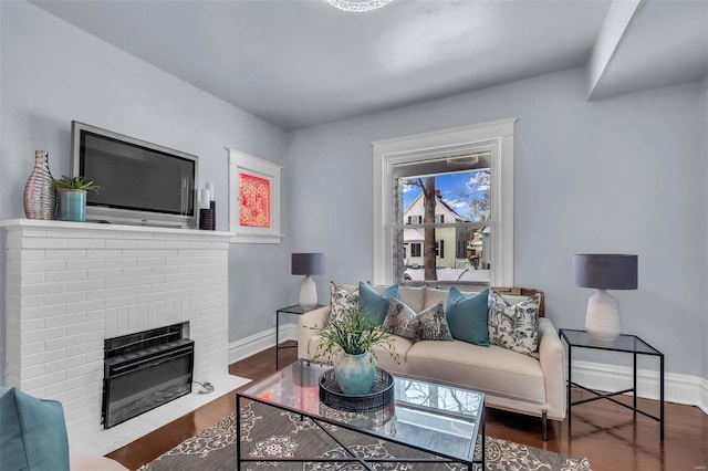 living room with a fireplace, baseboards, and wood finished floors