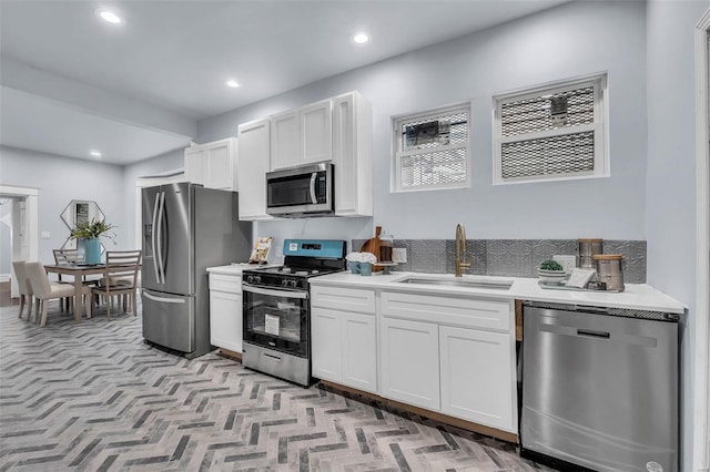 kitchen featuring white cabinets, light countertops, a sink, and appliances with stainless steel finishes