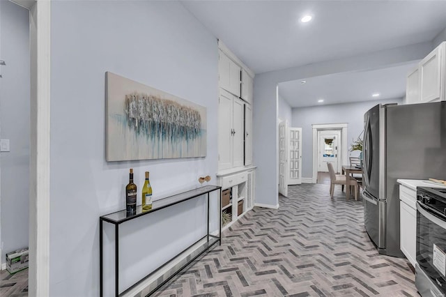 kitchen featuring light countertops, stainless steel electric stove, brick floor, white cabinetry, and recessed lighting