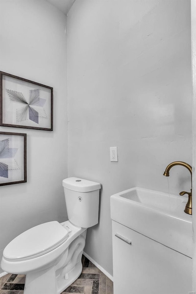 bathroom with vanity, baseboards, and toilet