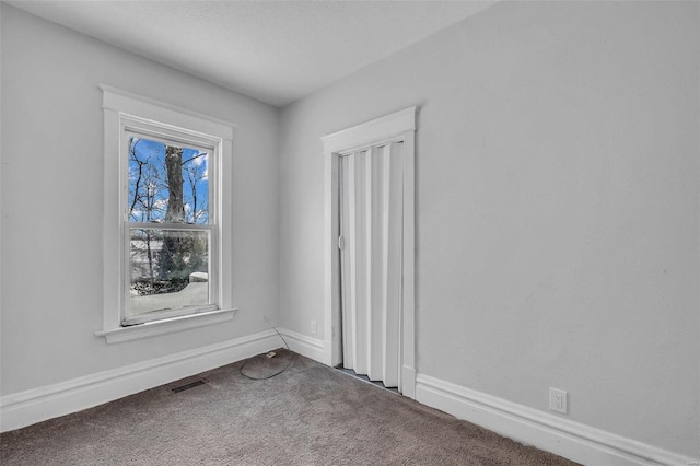 carpeted spare room featuring visible vents and baseboards