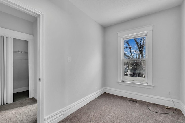 carpeted empty room with visible vents and baseboards