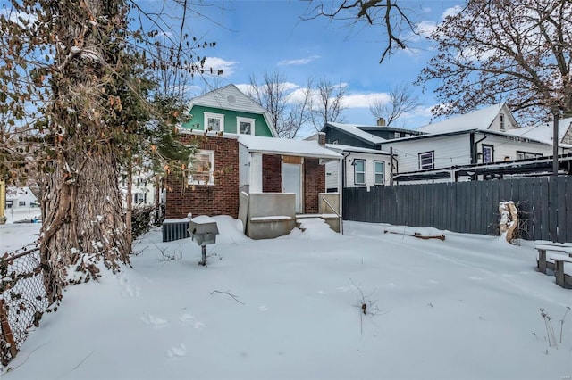 view of front of property with brick siding, fence, and central AC unit