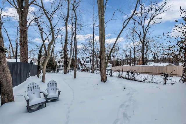 snowy yard featuring a fenced backyard