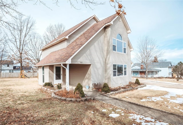 view of home's exterior with a shingled roof and fence