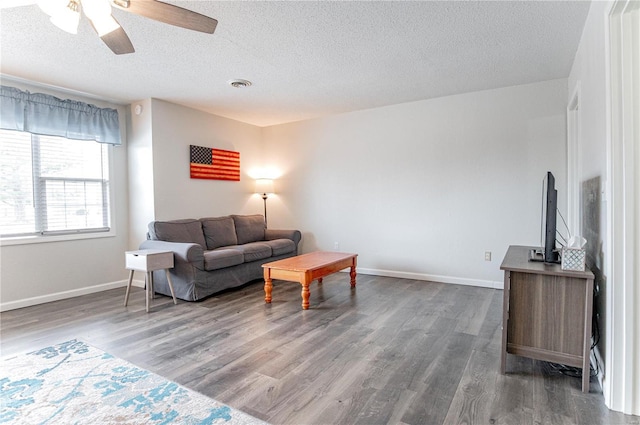 living area with baseboards, a textured ceiling, visible vents, and wood finished floors