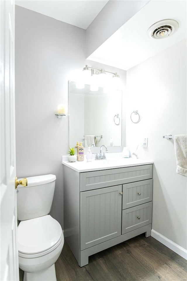 bathroom featuring baseboards, visible vents, toilet, wood finished floors, and vanity